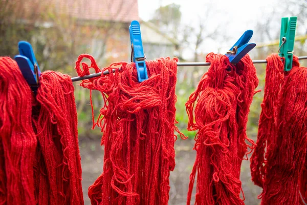 Woolen colorful threads are hanging on a clothesline with clothespins outdoor