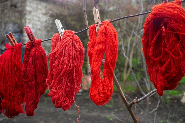 Woolen colorful threads are hanging on a clothesline with clothespins outdoor