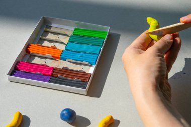 Masadaki plastik maddeden çocuk kalıpları. Çocuklar renkli plastik ellerle, çocuklar eğitici oyuncaklarla.