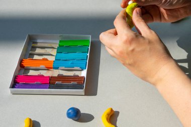 Masadaki plastik maddeden çocuk kalıpları. Çocuklar renkli plastik ellerle, çocuklar eğitici oyuncaklarla.