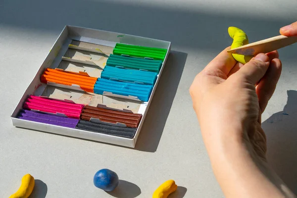 Masadaki plastik maddeden çocuk kalıpları. Çocuklar renkli plastik ellerle, çocuklar eğitici oyuncaklarla.