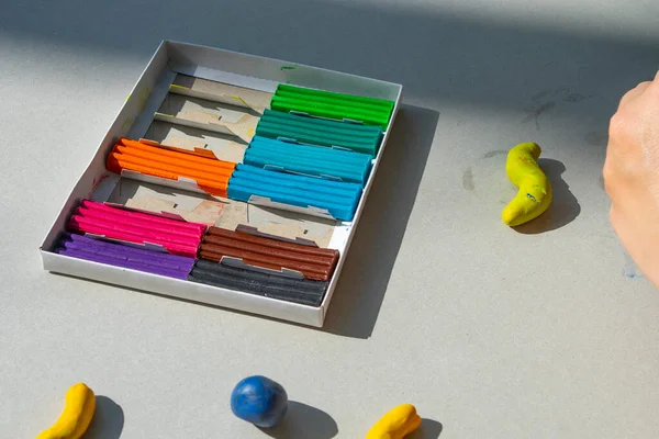 Masadaki plastik maddeden çocuk kalıpları. Çocuklar renkli plastik ellerle, çocuklar eğitici oyuncaklarla.