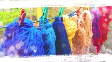 Yünlü renkli iplikler dışarıda çamaşır mandallarıyla bir çamaşır ipinde asılı.
