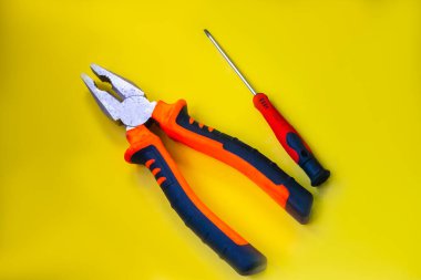 Sarı arka planda bir takım araçlar. İnşaat, DIY konsepti. Ekipman, iş yeri. Tornavida, mezura ve pense..
