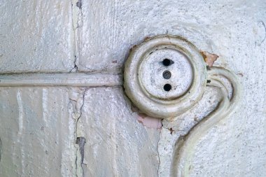 Duvarda eski tip bakalit lamba düğmesi var.