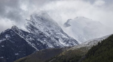 Sisin ve bulutların tepesinde, kayalık yamaçlarda. Dağlarda kötü hava, sabah manzarası.