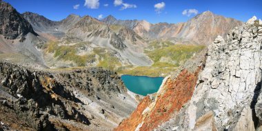 Mavi su gölü güneş ışığıyla çevrili kayalar, panoramik manzara