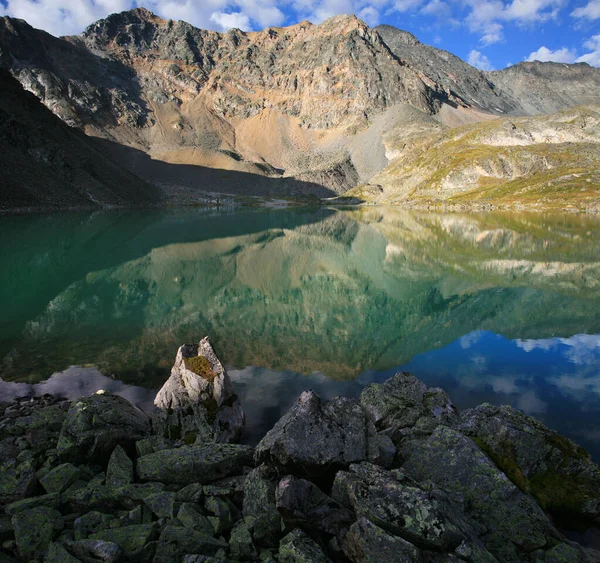 在清澈湖水中反射的岩石和多云的天空 — 图库照片