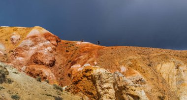 Altai 'nin güneyindeki dağlarda çok renkli bir çöl kabartması. Karanlık, fırtınalı bir gökyüzünün arka planında.
