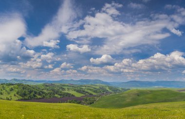 Yeşil tepelerin ve mavi gökyüzünün manzarası bulutlu, kırsal
