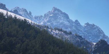 Sabahları dağ zirveleri, mavi gökyüzüne karşı kayalık tepeler.