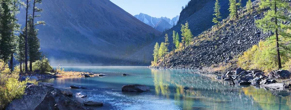 A beautiful lake in the mountains of Altai, banner. Forest on the shore, morning view.
