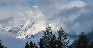 Bulutlarda karla kaplı dağ zirveleri. Dağlarda gezmek, tırmanmak.
