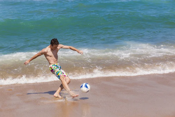 Menino chutando bola praia — Fotografia de Stock