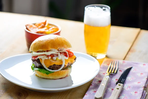 Hamburger with beer and fries in the background ready to be eate