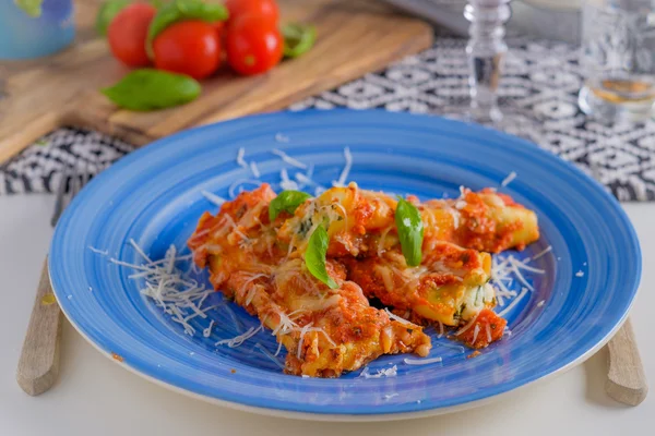 Plato de pasta de canelones con salsa de tomate en un plato azul con a —  Fotos de Stock