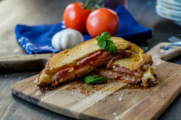 Sandwich grillé avec du basilic et des tomates en arrière-plan — Photo