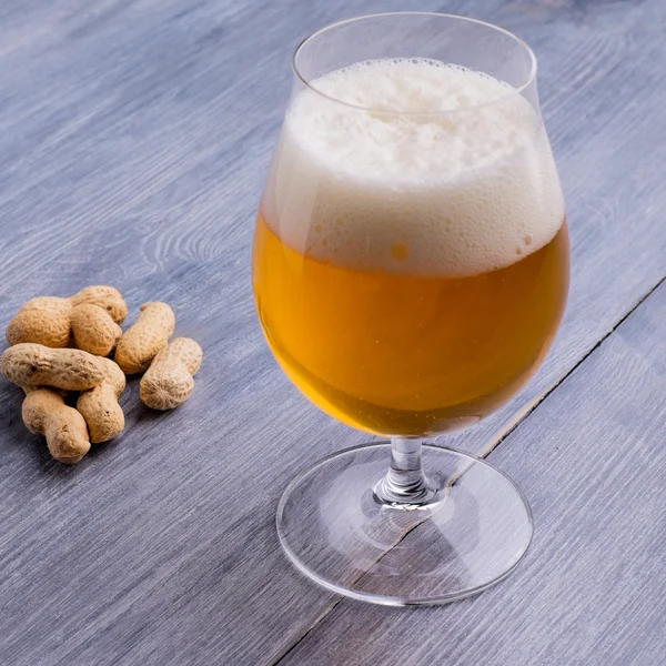 Beer with foam and peanuts on the side — Stock Photo, Image