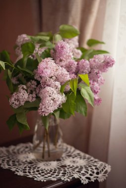 Durgun yaşam. Pencerenin yanında bir demet leylak dalı..