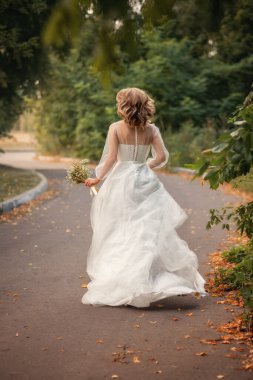 Gelinlikli bir gelin yol boyunca koşuyor..