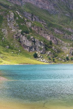 Alplerin ortasındaki dağ gölü. Mavi göllü yeşil dağda bir yaz. Alp dağları, ışık ve bulutların gölgesi..