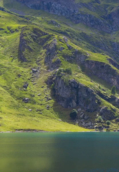 Alplerin ortasındaki dağ gölü. Mavi göllü yeşil dağda bir yaz. Alp dağları, ışık ve bulutların gölgesi..