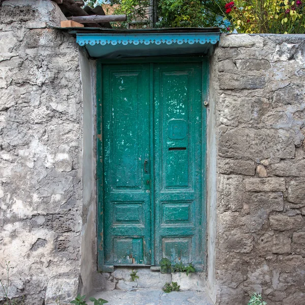 Ancien mur de pierre porte en bois de couleur verte — Photo