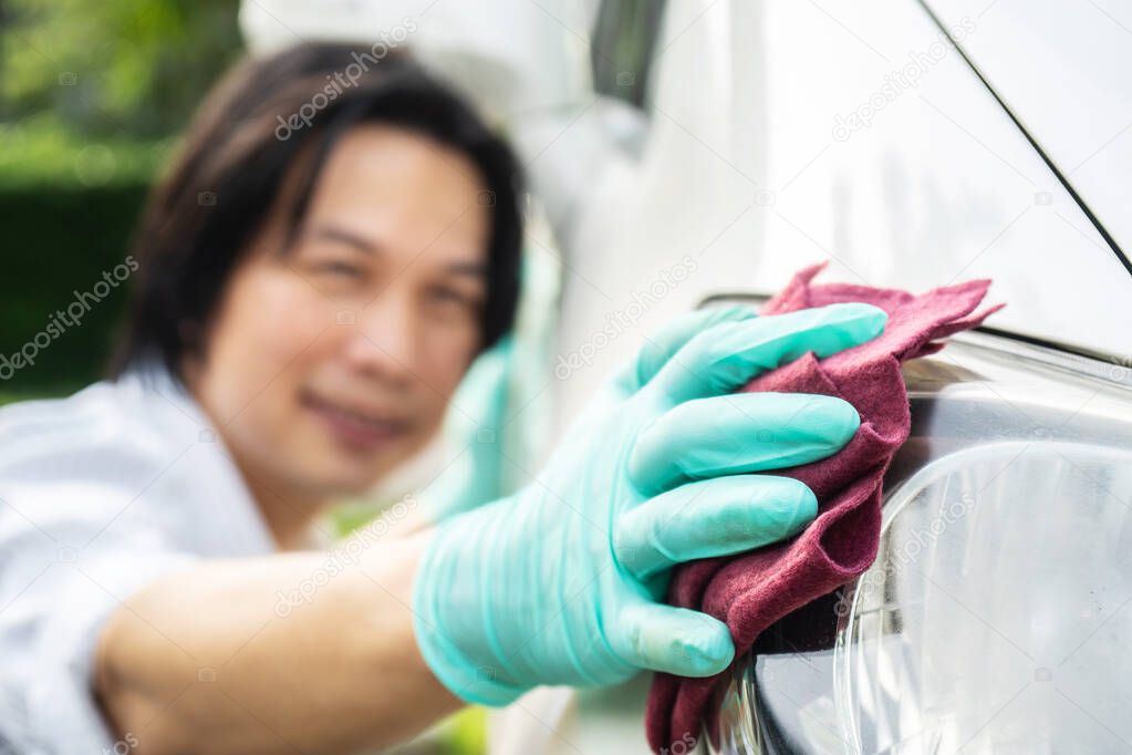 Car cleaning. Hand man in gloves cleaning the headlights of the car and wipes to shine.