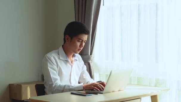 年轻的亚洲男人坐在桌旁用笔记本电脑 漂亮的亚洲女人给他端来一杯咖啡 以支持 鼓励和帮助他下班后放松 — 图库视频影像