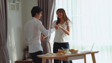 Genç ve mutlu Asyalı çift birlikte dans ediyor. Birlikte gülüyor, evde yemek hazırlıyor, kaygısız, neşeli karı ve koca sağlıklı romantik yemek pişiriyor. Modern mutfakta müzik dinliyor.