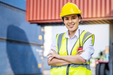 Asian female engineer wearing protection standing confidently crossed her arms in the cargo area of the ship yard