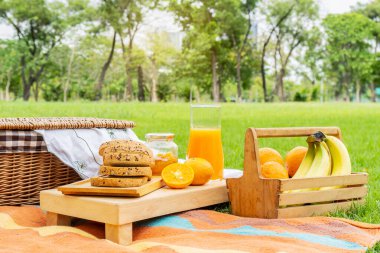 Meyve, portakal, muz ve ekmekle yaz pikniği, reçel. Parkta portakal suyu ve piknik sepetiyle piknik. Doğada taze meyve. Parkta iki kişilik bir randevu.