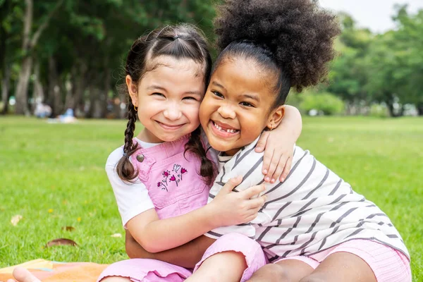 两个非洲裔美国人快乐的小女孩坐在垫子上 在花园里彼此热爱地拥抱 — 图库照片