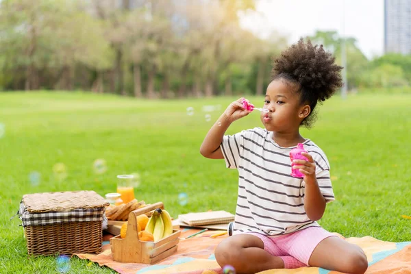 快乐的小非洲裔美国卷发女孩在公园里独自吹肥皂泡 黑发风格 — 图库照片