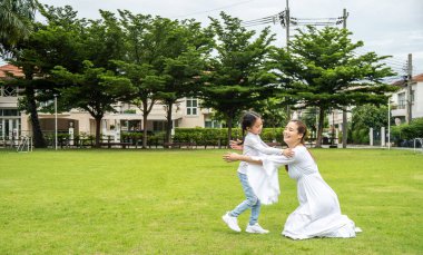 Parkta aile eğlencesi. Kız annesine koşuyor, annesi kucaklaşmak için kollarını açıyor.