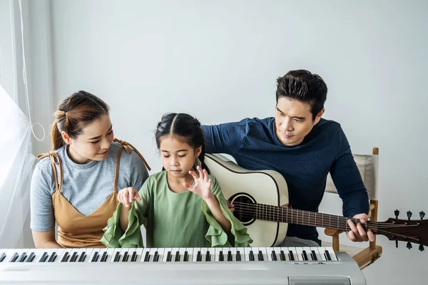 Szczęśliwa Mała Azjatycka Córka Gra Pianinie Matką Ojcem Grać Gitarze — Zdjęcie stockowe