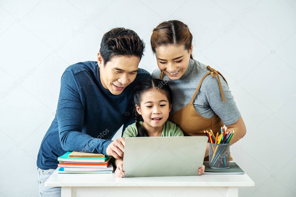 Happy young Asian family using at the laptop to surf internet together at home, , relaxing at home for lifestyle concept