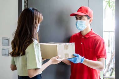 Kırmızı üniformalı teslimatçı, bir kadın müşteriye paket kutusu taşıyor. Kurye hizmeti kavramı.