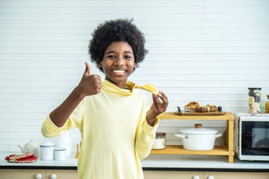 Sevimli, mutlu küçük çocuk sabah kahvaltıda tatlı reçelli tost yedikten sonra baş parmağını kaldırıyor.
