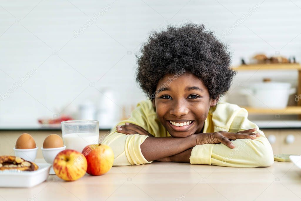 Close up smiling little boy drink glass of milk, sitting at wooden table in kitchen, adorable child kid enjoying organic food yogurt, getting vitamins and calcium, children healthcare concept