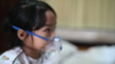 Solunum hastalığına yakalanan ve buharla tedavi edilen astım maskesi ile solunum tedavisi gören Asyalı hasta kız. 