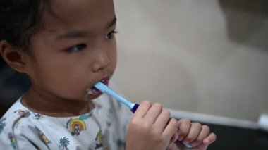 Asyalı hasta kız hastanedeki tuvalette dişlerini fırçalıyor.