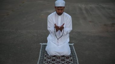 Genç Asyalı Müslüman adam gündüz dua ediyor, Ramazan festivali konsepti.