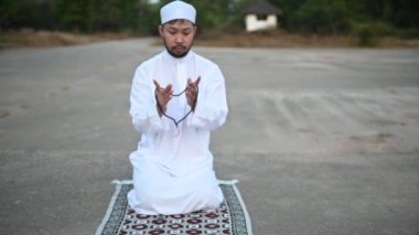 Genç Asyalı Müslüman adam gündüz dua ediyor, Ramazan festivali konsepti.