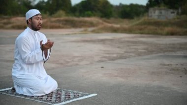 Genç Asyalı Müslüman adam gündüz dua ediyor, Ramazan festivali konsepti.