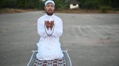 Genç Asyalı Müslüman adam gündüz dua ediyor, Ramazan festivali konsepti.