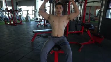 Spor salonunda kaslı Asyalı bir adam, vücut ağırlığı eğitimi. 