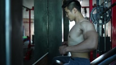 Büyük kaslı Asyalı adam spor salonunda ağırlık çalışması yapıyor.