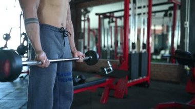 Büyük kaslı Asyalı adam spor salonunda ağırlık çalışması yapıyor.