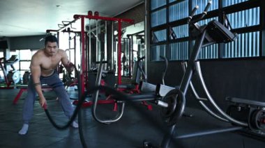 Büyük kaslı Asyalı adam spor salonunda ağırlık çalışması yapıyor.